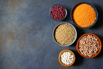 Assortment of legumes: beans and lentils. Raw healthy food. Vegetable protein. Dark background. Top view. Space for text