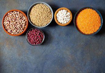 Assortment of legumes: beans and lentils. Raw healthy food. Vegetable protein. Dark background. Top view. Space for text
