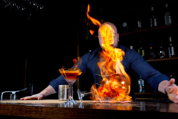 Fiery show at the bar. The bartender makes hot alcoholic cocktail and ignites bar. Bartender prepares a fiery cocktail. Fire on bar.