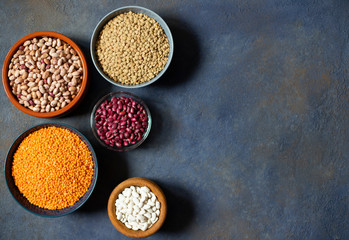 Assortment of legumes: beans and lentils. Raw healthy food. Vegetable protein. Dark background. Top view. Space for text