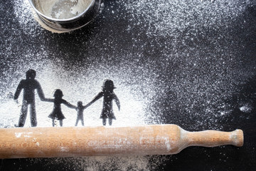 Figure flour in the form of family figures on a black table. Cooking pizza.
