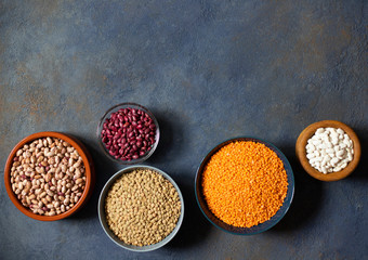 Assortment of legumes: beans and lentils. Raw healthy food. Vegetable protein. Dark background. Top view. Space for text