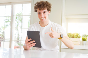 Young man using touchpad tablet very happy pointing with hand and finger