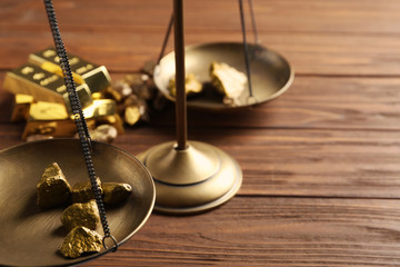Scale pan with gold lumps on wooden table, closeup. Space for text