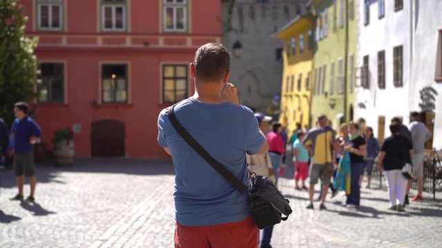 Man standing in the old town and doing photos of the architecture