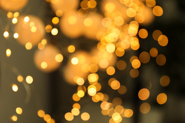 Blurred view of gold lights on dark background. Bokeh effect
