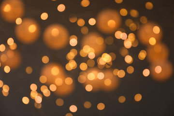 Blurred view of gold lights on dark background. Bokeh effect