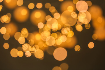 Blurred view of gold lights on dark background. Bokeh effect