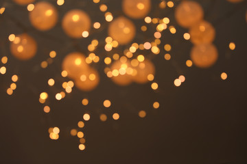 Blurred view of gold lights on dark background. Bokeh effect