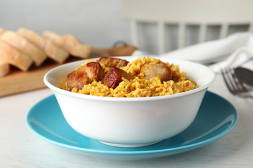 Bowl of tasty rice pilaf with meat served on table