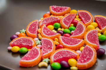 Colorful gummy candies,Candy bar on birthday party. many different dragees and marmalade. sweet pieces of colored marmalade on the dark brown table as part of a delicious dessert. Bright tasty dragees