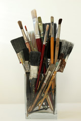 Old Paint Brushes in a Glass Jar with a White Background