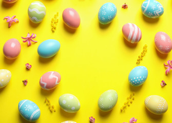 Frame made of painted Easter eggs on color background, space for text