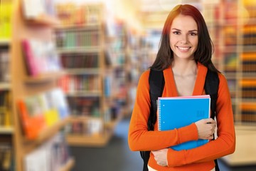 Beautiful female student in library with notebook