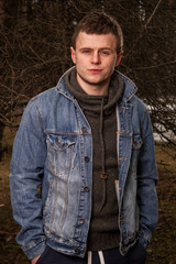 Portrait of young handsome man in blue jacket on ant forest background 