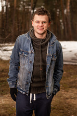 Portrait of young handsome man in blue jacket on ant forest background 