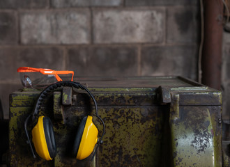 Fluorescent Orange health and safety eye protection glasses and yellow ear protection defenders on top of a workshop turning lathe machine