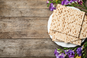 Fototapeta na wymiar Flat lay composition of matzo and flowers on wooden background, space for text. Passover (Pesach) Seder
