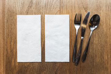 Top view of tissue napkins and cutlery over wooden table. For food banner.