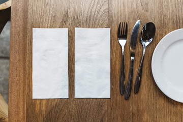 Top view of tissue napkins and cutlery over wooden table. For food banner.