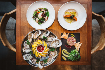 Fusion fine dining meal: Many kinds of Fresh Oyster, Ravioli in cream sauce with Grilled Salmon, Smoked Galician Octopus with Burrata Cheese and Spicy Bluefin Tuna Tartare.