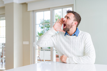 Fototapeta premium Handsome man wearing casual sweater shouting and screaming loud to side with hand on mouth. Communication concept.