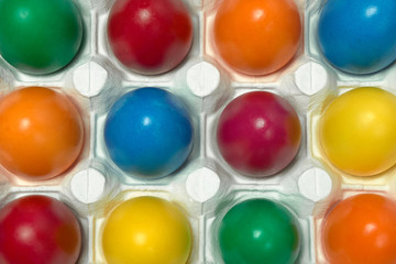 Many multicolored Easter eggs in white egg tray Festive tradition Close up Top view 