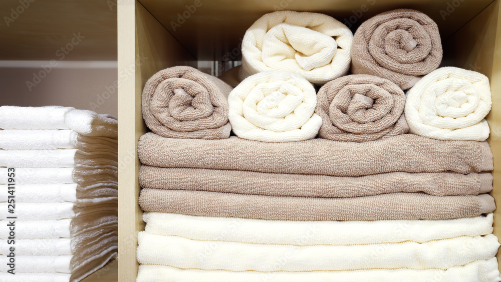 Poster white and brown beige towels folded and stacked on a shelf