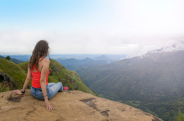Naklejka premium Young beautiful woman in the mountains, enjoying the view and beauty of nature.