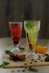two glasses with colored hot drinks from which steam comes. winter hot seasonal drinks