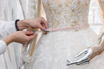 Dressmaker measuring waist of dress on mannequin