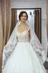 Fototapeta na wymiar Smiling bride fitting dress in wedding salon