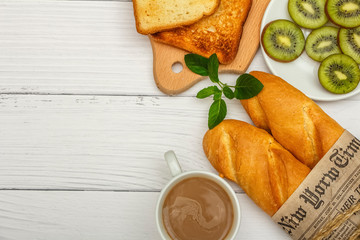 A cup of coffee, fresh bread, toast on a white woody background. Morning breakfast fresh bread with a cup of coffee. View from above.
