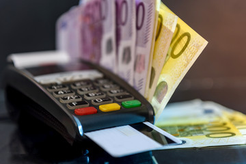Terminal with card and euro banknotes behind it