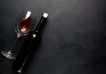 A bottle of wine and a glass of wine against a concrete background. Top view with copy space.