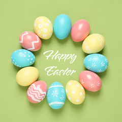 Frame made of colorful painted eggs and text Happy Easter on color background, top view