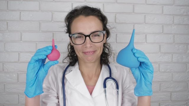 Cheerful doctor with enema. Cute nurse with glasses with medical pears.