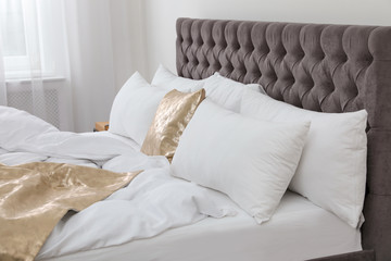 Soft pillows on comfortable bed in room. Modern interior design