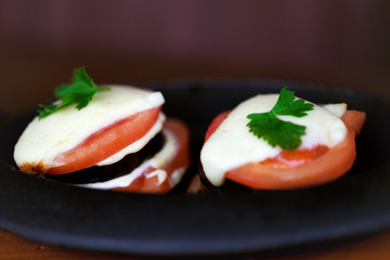 Baked eggplant with tomato, cheese and cilantro leaf in cast iron portion pan