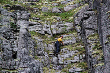 Caucasian white male rock climber in sportswear climbs a rock