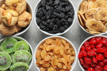 Bowls with different dried fruits on grey background, flat lay. Healthy food