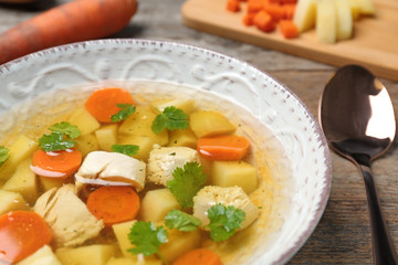 Dish with fresh homemade chicken soup on wooden table, closeup