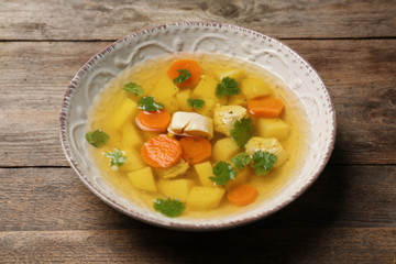 Dish with fresh homemade chicken soup on wooden table