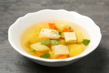 Dish with fresh homemade chicken soup on grey table