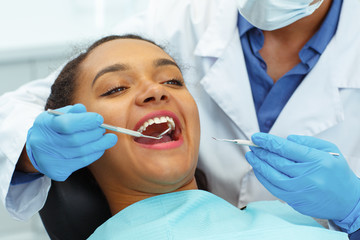 Close up of female patient being examined by dentist in clinic.