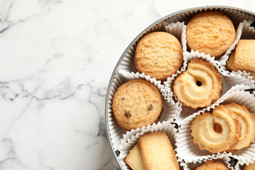 Tin box with Danish butter cookies on marble table, top view. Space for text