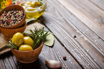 Closeup view of green olives oils and spices on kitchen table. Cooking concept