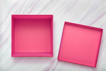 Flat lay of empty pink gift box with lid on natural marble texture. Pink cardboard box with cover....