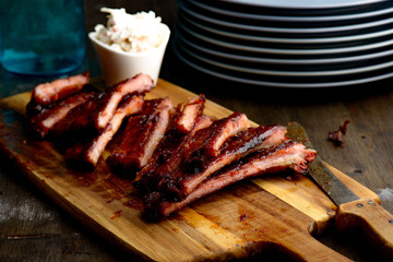 Smoked ribs ready to be eaten on wooden plate.​