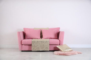 Stylish pink sofa against white wall in modern living room interior. Space for text